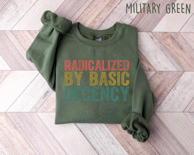 May include: A green sweatshirt with the text "RADICALIZED BY BASIC DECENCY" in a vintage style font with red, orange, yellow, and green colors.