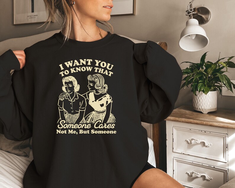 May include: Black sweatshirt with a white graphic print that says "I want you to know that someone cares not me, but someone". The graphic features two women in vintage clothing.