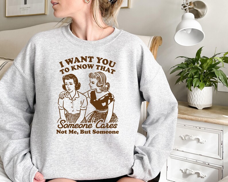 May include: Gray sweatshirt with a brown graphic print of two women. The text on the graphic reads "I want you to know that someone cares not me, but someone."