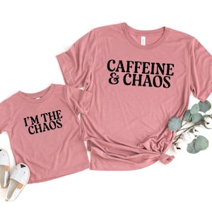May include: Two pink t-shirts with black text. The larger shirt says "CAFFEINE & CHAOS". The smaller shirt says "I'M THE CHAOS".