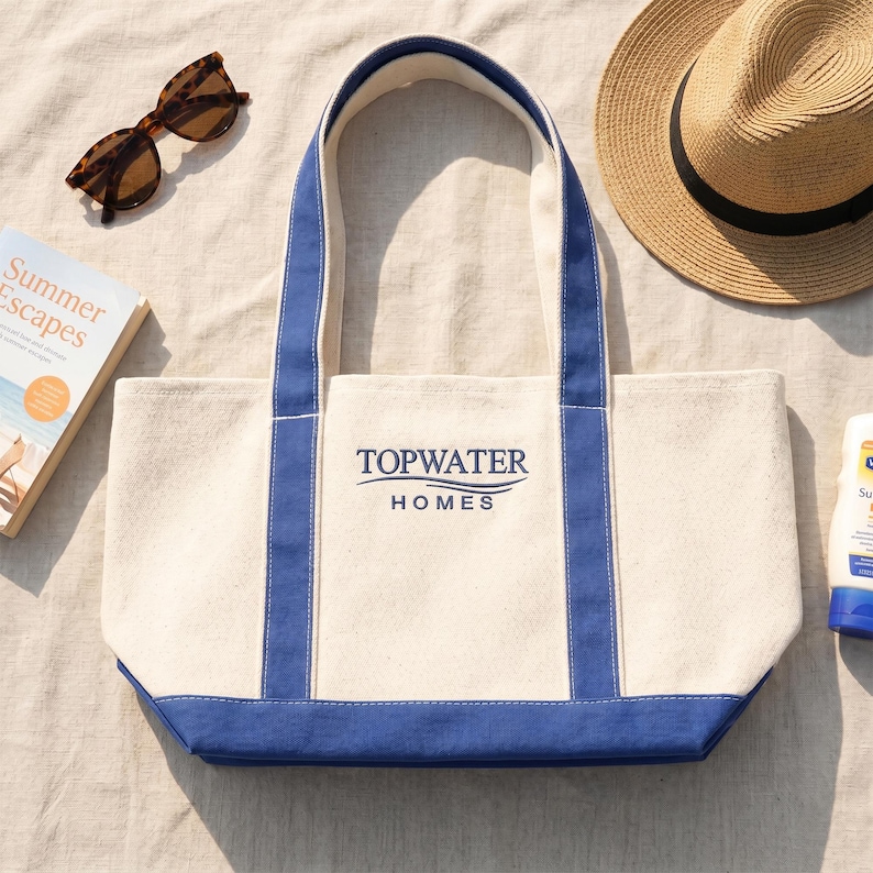 Custom logo tote bag for business branding with “Topwater Homes” print, beach lifestyle setting with summer accessories, promotional company tote