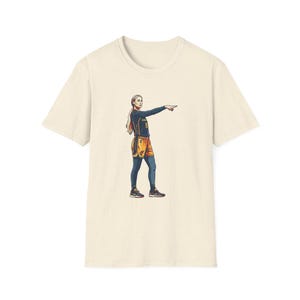 Puede incluir: Una camiseta de manga corta color crema con una ilustración gráfica de un jugador de baloncesto que viste una camiseta azul oscuro y pantalones cortos naranjas con el número 8, señalando a la derecha con mallas oscuras y zapatillas deportivas.
