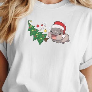Camiseta de Natal Moo-Deng Hippo, Hipopótamo atrevido enfrentando árvore de Natal, Camiseta gráfica unissex, Camiseta divertida de Natal, Amante de hipopótamos animais