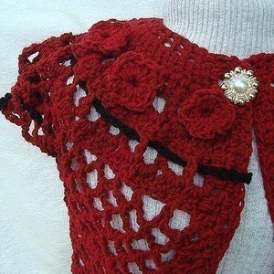May include: Red crocheted shawl with black trim and a pearl-like button.