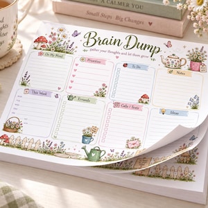 May include: A rectangular paper notepad titled Brain Dump with sections for On My Mind, Priorities, To Do, Notes, This Week, Errands, Calls/Texts, and Ideas. The page features floral illustrations, mushrooms, a teapot, and a garden fence.