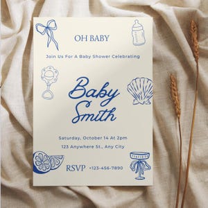 May include: A baby shower invitation featuring blue illustrations of baby-related items. The text includes "OH BABY" and "Baby Smith", along with event details and an RSVP number. The design is on a cream-colored background.