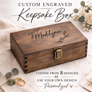 May include: A rectangular, wooden keepsake box with a dark brown finish. The box features a brass-colored clasp and is engraved with the name "Madilynn" and floral accents. Text on the image reads "Custom Engraved Keepsake Box" and "Personalized".