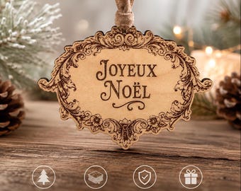 May include: A light-colored wooden ornament with an ornate, laser-engraved border and the text "JOYEUX NOËL" in the center. The ornament is suspended by a brown ribbon and features four circular icons below with text: BEAUTIFULLY ENGRAVED, MADE FROM MAPLE PLYWOOD, FINISHED WITH A CLEAR COAT, and READY TO GIFT.