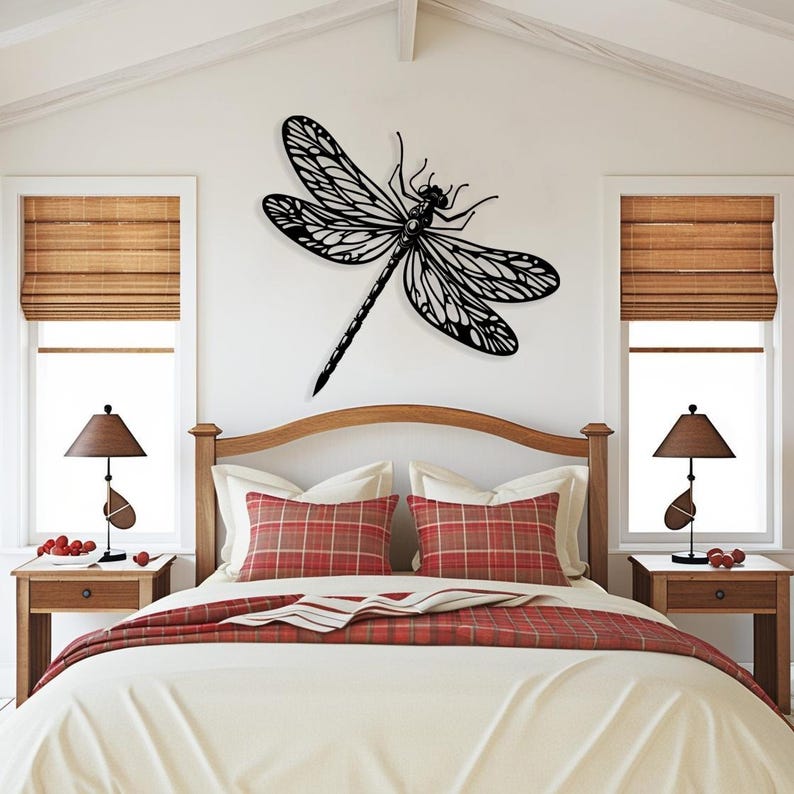 May include: A black metal dragonfly wall decor with intricate details, mounted on a white wall above a bed with red and white plaid pillows and a white bedspread.