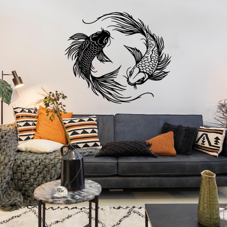 Puede incluir: Pegatina de pared de silueta en blanco y negro de dos peces koi nadando en c&iacute;rculo. La pegatina est&aacute; en una pared blanca sobre un sof&aacute; gris con almohadas.