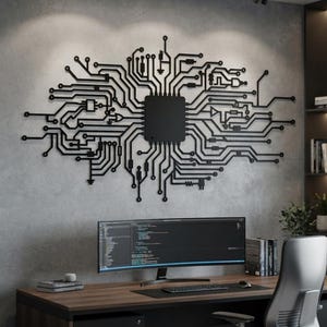 Könnte beinhalten: Ein großes, schwarzes, flaches Wandkunstobjekt mit einem komplexen, symmetrischen Leiterplattendesign, das eine zentrale rechteckige Prozessoreinheit und strahlenförmige Linien aufweist, montiert an einer grauen Wand.