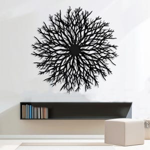 May include: Black metal wall decor in the shape of a large, circular, branching tree. The decor is mounted on a white wall above a black shelf with books.