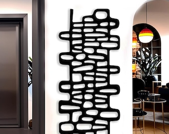 May include: A black, abstract wall art piece with a unique, open design. The artwork features a series of interconnected shapes and cutouts, creating a modern and artistic aesthetic. It is mounted on a white wall, adding a striking contrast.