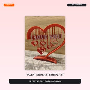 May include: A 3D printed orange heart-shaped display piece featuring the text I LOVE YOU suspended from the top arch. Several smaller heart outlines hang from vertical lines within the main frame, all supported by a curved base stand.