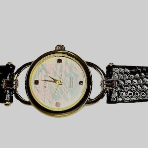 Puede incluir: Un reloj de cuarzo ADOLFO dorado con piedras preciosas, esfera de nácar y correa de cuero negro. La esfera del reloj tiene detalles en rojo y rosa. La correa tiene un patrón texturizado.