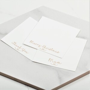 May include: Three white cards with different messages written in cursive on them. The messages are "Merry Christmas", "Mum", and "Thank You".