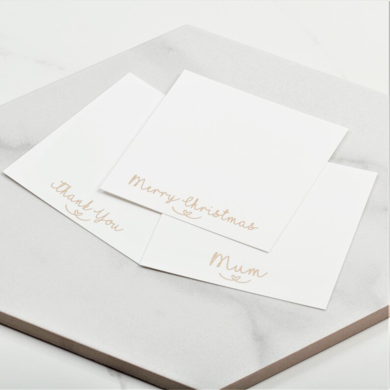 May include: Three white cards with different messages written in cursive on them. The messages are "Merry Christmas", "Mum", and "Thank You".