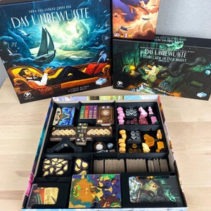 Könnte beinhalten: Ein Spielorganizer für das Brettspiel "Das Unbewusste: Schrecken in der Nacht". Der Organizer ist aus Pappe und hat verschiedene Fächer zum Verstauen der Spielkomponenten. Der Organizer ist mit Bildern aus dem Spiel verziert, darunter ein Leuchtturm, ein Schloss und ein Seeungeheuer.