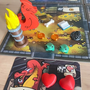 Può includere: Un pezzo da gioco di drago rosso con una fiamma gialla su una base di legno. Il drago è su una scacchiera con uno sfondo verde, marrone e giallo. Ci sono anche altri pezzi da gioco sulla scacchiera, tra cui un osso, un libro e una moneta. La scacchiera ha un bordo nero e il testo "12/12" nell'angolo in basso a destra.