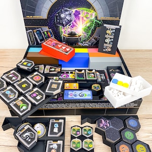 May include: A board game box labelled "GAIA PROJECT" with game components. The box has a space theme. Inside are cards, tokens, and game boards in black, orange, blue, and white. The game components are arranged in black trays. The game is in a box.