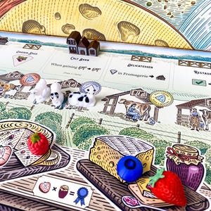 Peut inclure: Un jeu de société sur le thème du fromage. Le plateau présente une variété d'espaces liés au fromage, notamment un hangar de jardin, une étable à veaux, une épicerie fine et un restaurant. Il y a aussi des vaches miniatures et des morceaux de fromage sur le plateau.