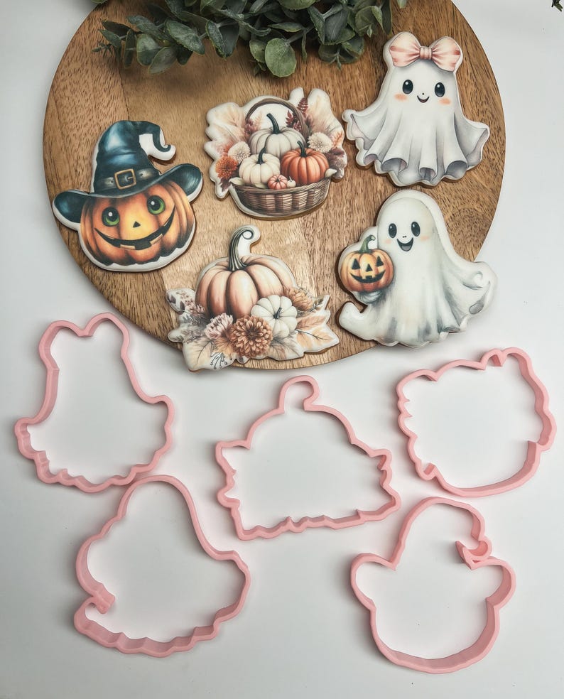 K&ouml;nnte beinhalten: Satz mit sechs Halloween-Ausstechern, darunter ein Geist, ein K&uuml;rbis, ein Hexenhut und drei verschiedene Herbstmotive. Die Ausstecher sind rosa und aus Kunststoff.