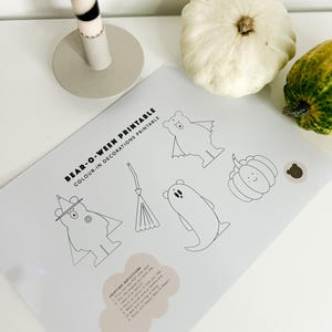 Könnte beinhalten: Ein ausdruckbares Malblatt mit Anweisungen zum Basteln von Halloween-Dekorationen. Das Blatt zeigt einen Bären, der als Hexe verkleidet ist, ein Gespenst, eine Fledermaus und einen Kürbis.