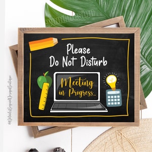 May include: A black chalkboard sign with yellow trim, reading "Please Do Not Disturb Meeting in Progress..." with a pencil, apple, laptop, lightbulb, and calculator illustration.