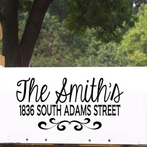 May include: White mailbox with black lettering that reads "The Smiths" and "1836 South Adams Street". The mailbox has a decorative scroll design below the text.