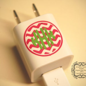 Könnte beinhalten: Ein weißes Handy-Ladegerät mit einem runden Aufkleber mit pink-weißem Chevron-Muster und einem grünen Monogramm in der Mitte. Der Aufkleber lautet "Kreative Corner Designs Original Vinyl Design 2013 Copyrighted Image".