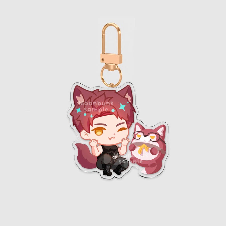 May include: An acrylic keychain featuring a cartoon character with red hair, wolf ears, and a tail, wearing a black tank top and pants. Beside the character is a small, round, red creature wearing glasses. The text moonbuns sample is visible.