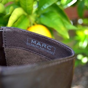 May include: Close-up of the inside of a brown leather boot with the text "MARC GERMANY  REINLEATHER" printed on the insole.