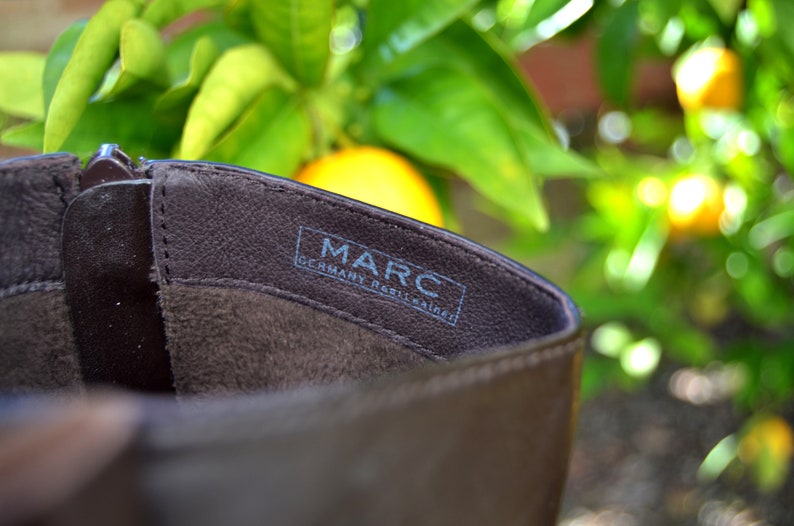 May include: Close-up of the inside of a brown leather boot with the text "MARC GERMANY  REINLEATHER" printed on the insole.