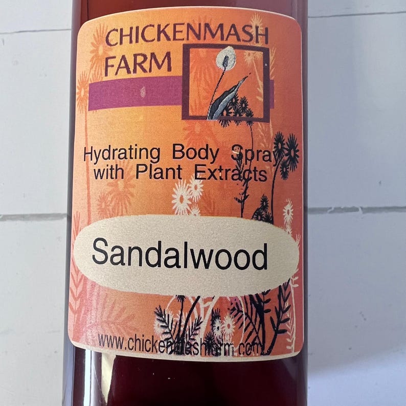 Puede incluir: Una botella de spray hidratante corporal con extractos de plantas. La etiqueta presenta el texto "Chickenmash Farm" y "Sandalwood" en un &oacute;valo color crema. El fondo es un degradado de naranja y rojo.