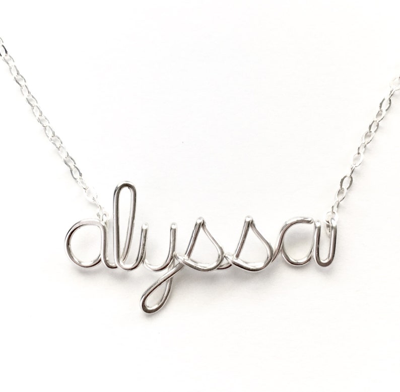 May include: A silver necklace with the name "Alyssa" spelled out in wire.