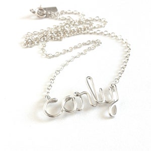 May include: A silver necklace with a delicate chain and a wire-formed name pendant that says "Carly".