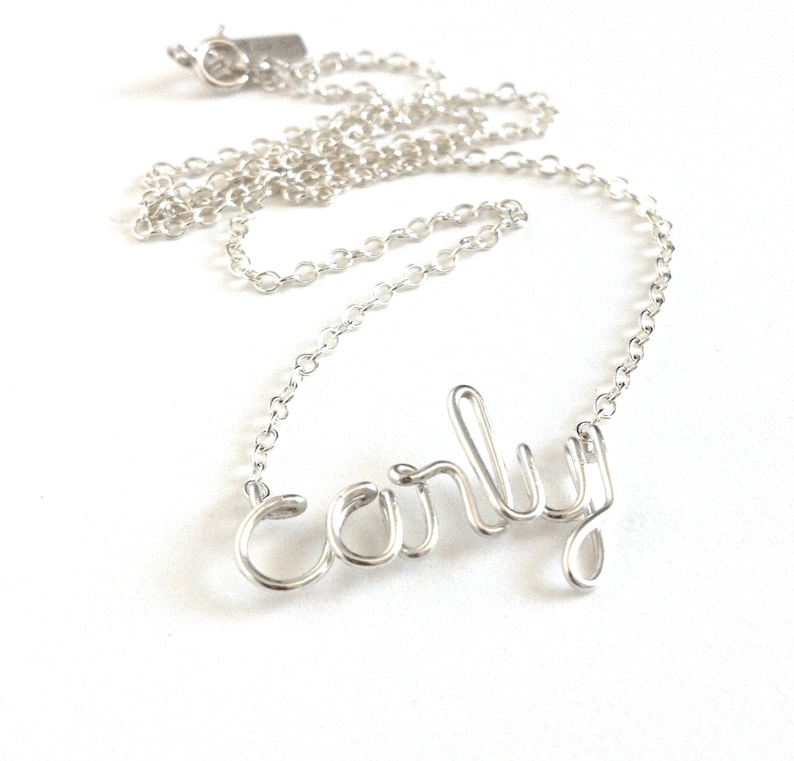 May include: A silver necklace with a delicate chain and a wire-formed name pendant that says "Carly".