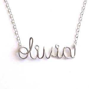 May include: A silver necklace with the name "Olivia" spelled out in cursive wire.