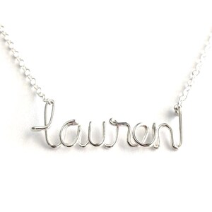 May include: A silver necklace with the name "Lauren" spelled out in wire.