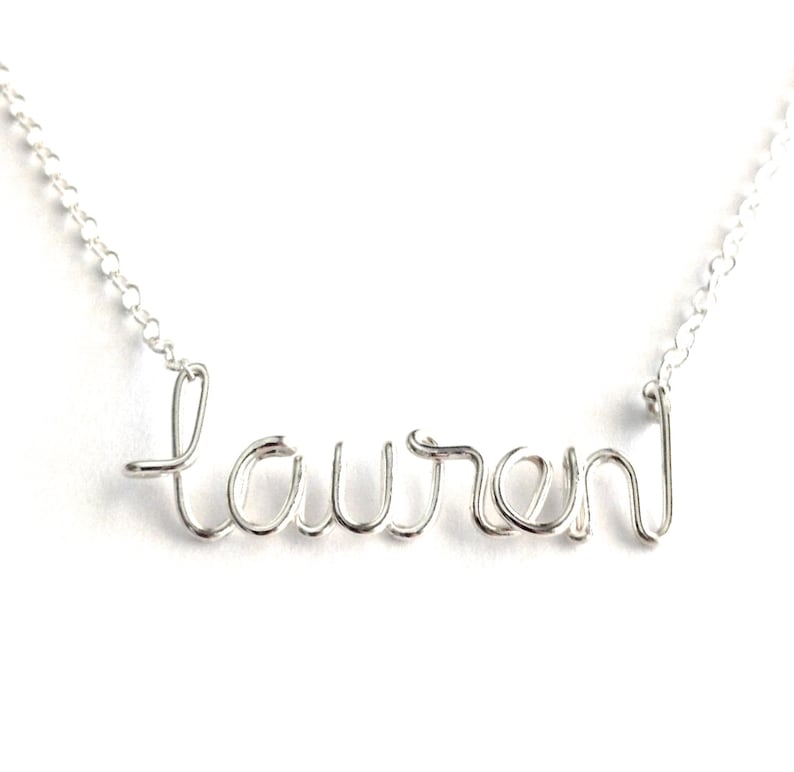 May include: A silver necklace with the name "Lauren" spelled out in wire.