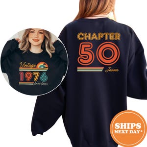 May include: A black long-sleeve sweatshirt featuring a graphic on the back that reads CHAPTER 50 with the name Janna in orange and yellow text. A circular inset shows the front of the sweatshirt with the text Vintage 1976 Limited Edition.