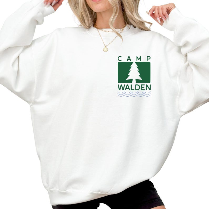 A woman wearing a white sweatshirt with a green and white logo on the front.