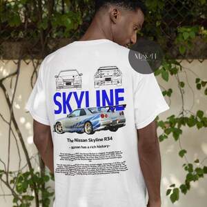 May include: White t-shirt with a blue and white graphic of a Nissan Skyline R34 car. The text "SKYLINE" is printed in blue above the car. The text "The Nissan Skyline R34 - Nissan has a rich history" is printed below the car.