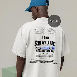 May include: White t-shirt with a black and white illustration of a Nissan Skyline R34 car. The text "1998 SKYLINE" is printed in black above the car. The text "NISSAN SKYLINE R34" is printed in black below the car. The text "The Nissan Skyline (Japanese: 日産・スカイライン, Hepburn: Nissan Sukairain) is a brand of automobile originally produced by the Prince Motor Company starting in 1957, and then by Nissan after the two companies merged in 1967." is printed in black below the car.