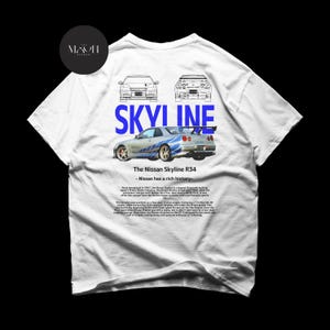 May include: White t-shirt with a blue and white graphic of a Nissan Skyline R34 car. The text "SKYLINE" is printed in blue above the car. The text "The Nissan Skyline R34 - Nissan has a rich history" is printed below the car.