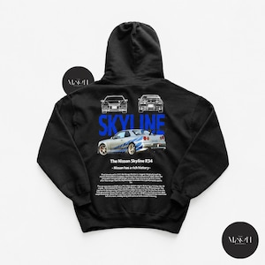 Könnte beinhalten: Ein schwarzer Kapuzenpullover mit einem Grafikdruck auf der Rückseite. Das Design zeigt einen silbernen Nissan Skyline R34, das Wort SKYLINE in Blau, zwei Strichzeichnungen von Autos und einen weißen Textblock zur Geschichte des Fahrzeugs.