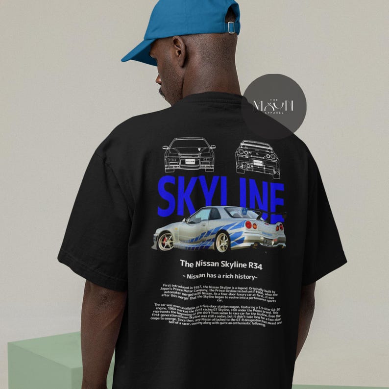 May include: Black t-shirt with a blue and white graphic of a Nissan Skyline R34 car. The text "SKYLINE" is printed in blue above the car. The text "The Nissan Skyline R34 - Nissan has a rich history." is printed below the car.