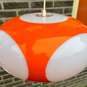 Op de afbeelding: Een grote, ronde, oranje en witte hanglamp met een modern ontwerp.