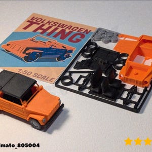 May include: An orange and black 1:50 scale model of a Volkswagen Thing. The model is assembled and next to unassembled parts on a black sprue. A vintage-style poster with the words "VOLKSWAGEN THING" is in the background.