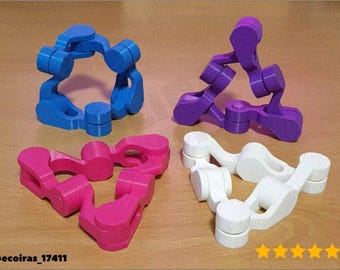 May include: Four brightly coloured geometric puzzles in blue, purple, pink, and white. Each puzzle has a unique shape, with interlocking pieces. The puzzles are arranged on a light brown surface, showcasing their vibrant colours and intricate designs.